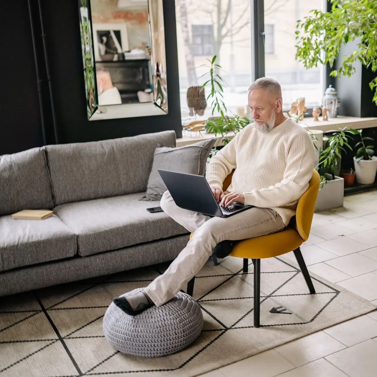 A developer writing code on a laptop by a bright window with plants